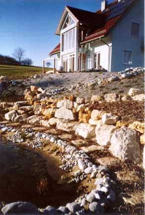 Trockenmauer mit xerothermer Bepflanzung und Kies als mineralische Mulchschicht und Teich - kurz nach Fertigstellung