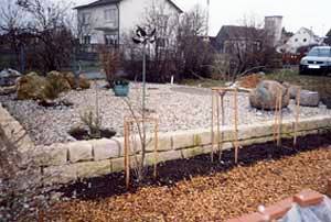 mit Trockenmauer eingefasster Kiesgarten mit Messing-Kunstwerk und Findling